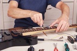 Guitar master crowning frets on the electric guitar neck with fret files.