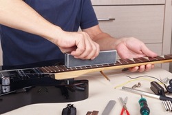 Guitar master aligns the frets on guitar neck with leveling bar.
