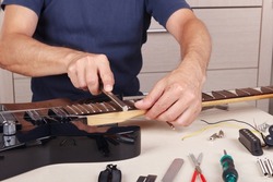 Guitar repairer crowning frets on the guitar neck with fret files.