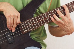 Hands of rock musician playing the electric bass guitar