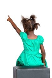 Rear view of little African girl in green dress pointing with finger. Isolated on white background.