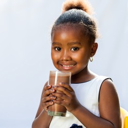 Close up portrait of adorable African girl drinking milk chocolate drink.Isolated on light background.