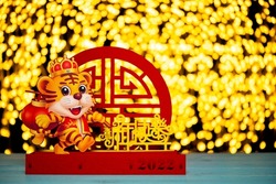 Chinese New Year of tiger 2022 mascot paper cut in front of lights the Chinese means Happy New Year 