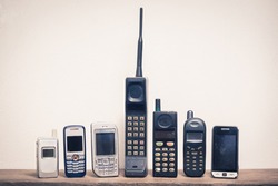 Group of old and obsolete mobile phone or cell phone on old wood with a light rough background