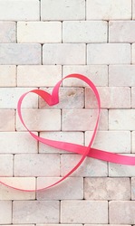 Gift ribbon in a heart shape on rustic stone background