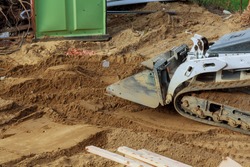 Bulldozer moving, leveling ground at construction site in ground using shovels
