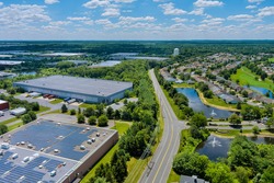 Aerial panoramic view on solar panels on absorb sunlight sustainable energy of building warehouse roof near small American town