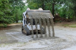 Bobcat tractor moving and unloading gravel on old road reconstruction site