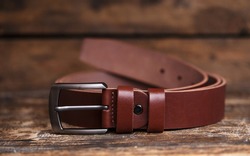 Men's leather trouser red belt in the background of aged wood. Men's fashion accessories closet. Genuine leather, handmade