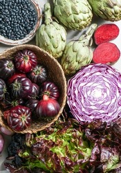 purple and red, violet vegetables on the purple background, top view. purple  artichoke, tomatoes, oniones, blueberries, salad                            