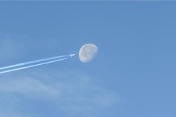 A jet plane flying past the moon.