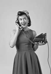 Beautiful woman in retro style with perfect hair and make up , speaking via vintage phone.