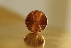A US penny standing upright on a sheet of golden metal