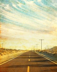 An empty desert road in Arizona's Mojave desert with grunge stains and spots.  Image has a distinct paper texture visible at 100%.
