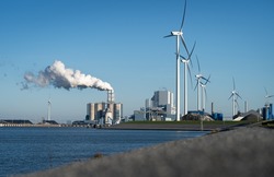 Fossil fuel (coal) power station and wind turbines in the Eemshaven generating power. Energy transition concept.