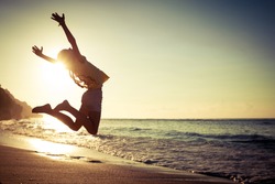 teen girl jumping on the beach at the day time