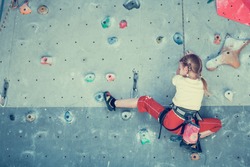 little girl climbing a rock wall indoor