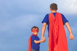 Father and son playing superhero at the day time. People having fun outdoors. Concept of friendly family.