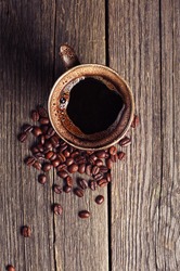 Cup of coffee and beans on vintage wooden background. Top view
