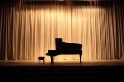 Grand piano at concert stage with brown curtain