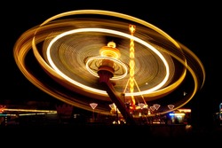Horizontal photo of funfair carousel in movement taken at night.