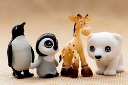 Plastic toy figurines. Penguins, giraffe and white teddy bear.