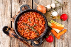 classic italian bolognese sauce stewed in stewpot with ingredients on wooden table, top view
