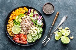 Vegetarian salad Buddha bowl dish with brown rice, avocado, pepper, tomato, cucumber, chickpea, chia seeds, fresh lettuce salad and cashew nuts. Healthy eating trend, superfood. Top view