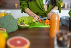 Cropped photo of a chef cutting carrots on a plastic board