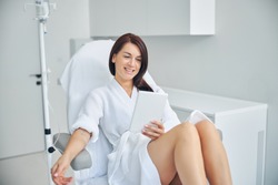 Smiling woman with dark hair getting an intravenous vitamin drip treatment at a beauty salon