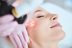 Close up portrait of a young woman patient receiving a laser treatment in a spa salon