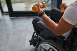 Man with physical disability using a wheelchair holding sports equipments in hand