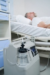 Recumbent male patient connected to portable oxygen concentrator