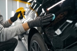 Experienced service station worker removing contaminants from automobile surface