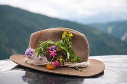 brown felt hat decorated with alpine flowers - austrian mountains in the background