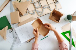 Top view of woman hand with box on the designer's desk, she designs new packaging