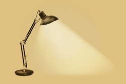 Illuminated vintage rusty desk lamp with flexible arms on a sepia background