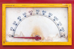 Vintage weathered meter with red needle in a red casing with yellow frame