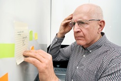 Elderly man looking at notes. Forgetful senior with dementia, memory problem, health concept
