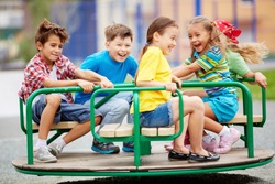 Image of joyful friends having fun on carousel outdoors 