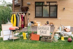 Garage sale in backyard: various toys, household stuff and clothes putting on sale