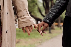 Hands of amorous intercultural girlfriends taking walk in park at leisure