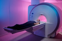 Young woman lying on long table of medical equipment before undergoing mri scan examination