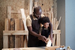 Waist up portrait of loving black father and son bonding together in carpentry workshop