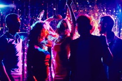 Group of guys and girls dancing in the night club