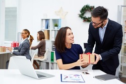 Young businessman giving his colleague Christmas present in office