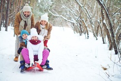 Young family sitting on a sled in the snow