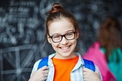 Happy little girl wearing glasses looking at camera