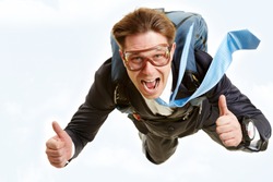 Conceptual image of happy man flying with parachute and showing thumbs up