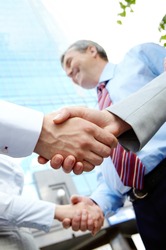 Vertical image of rows of partners handshaking outdoors on background of modern building